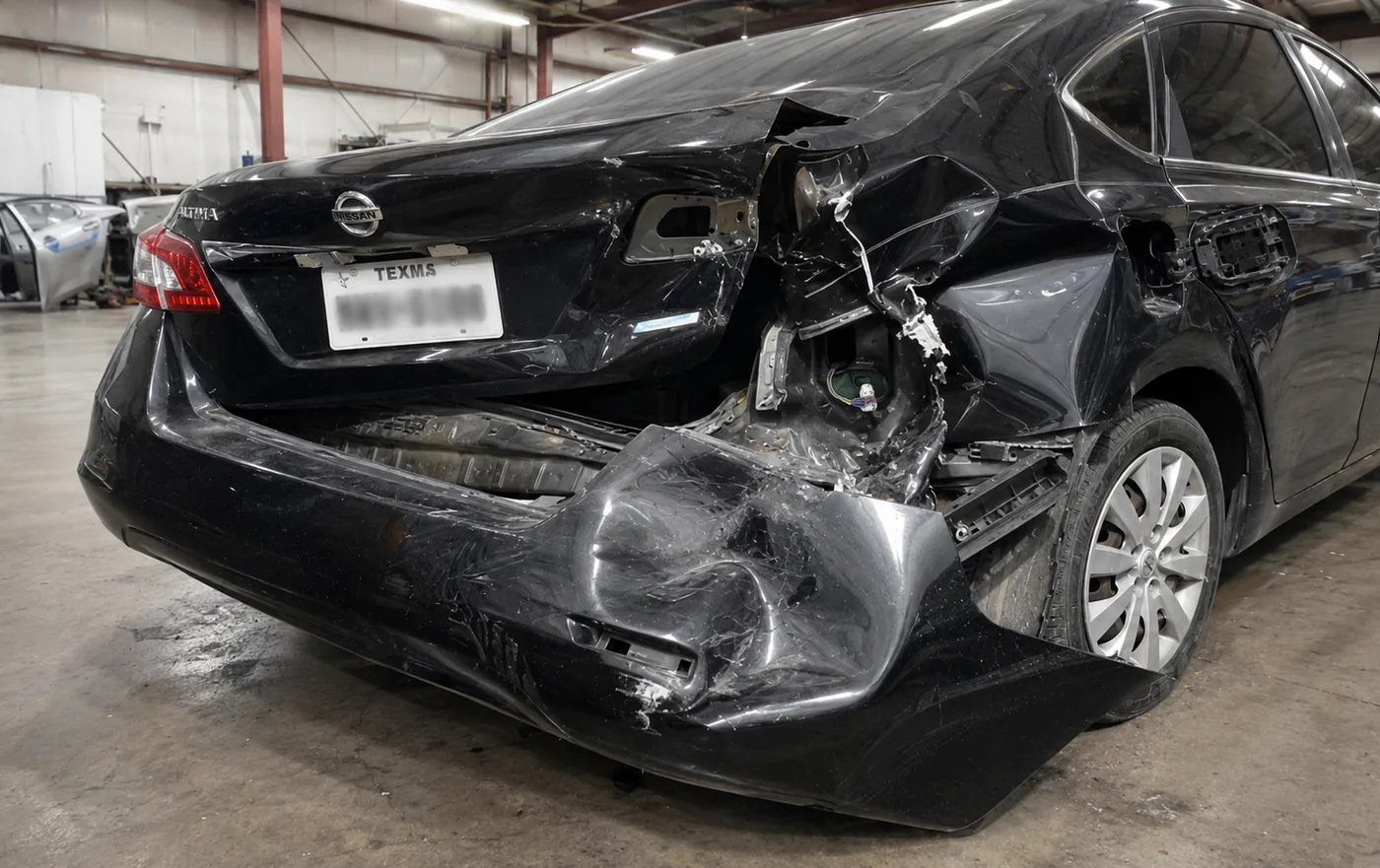 Nissan Altima con daño severo en la esquina trasera, antes de la reparación